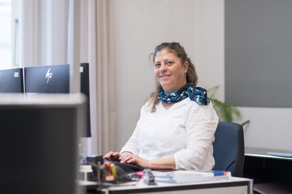 Das Bild zeigt Beatrice an ihrem Arbeitsplatz voller gesamtschulischen Projekte und Anlässe