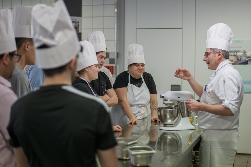 Die Lehrperson erklärt den Lernenden: Es zählt nicht nur der Geschmack, sondern auch die Konsistenz. Die perfekte Mayonnaise fliesst wie ein Faden vom Löffel.
