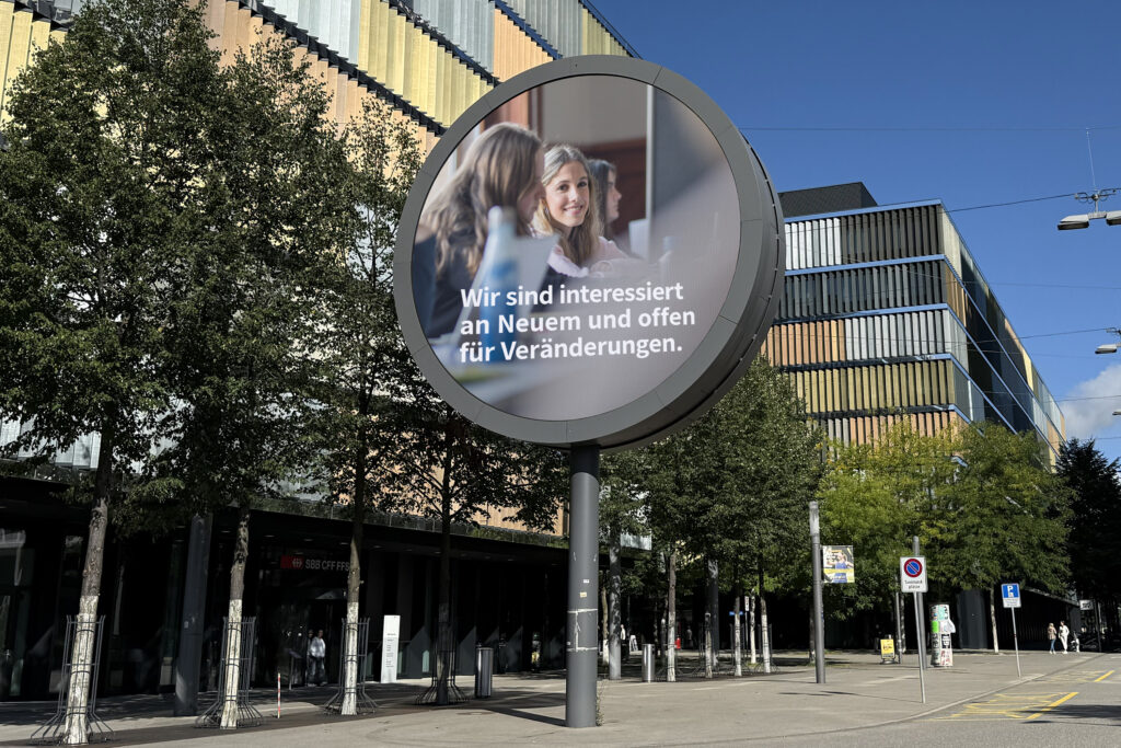 Das Bild zeigt das Leitbildsujet 2025, das in der riesigen Uhr der SBB in Wankdorf ausgestrahlt wird.