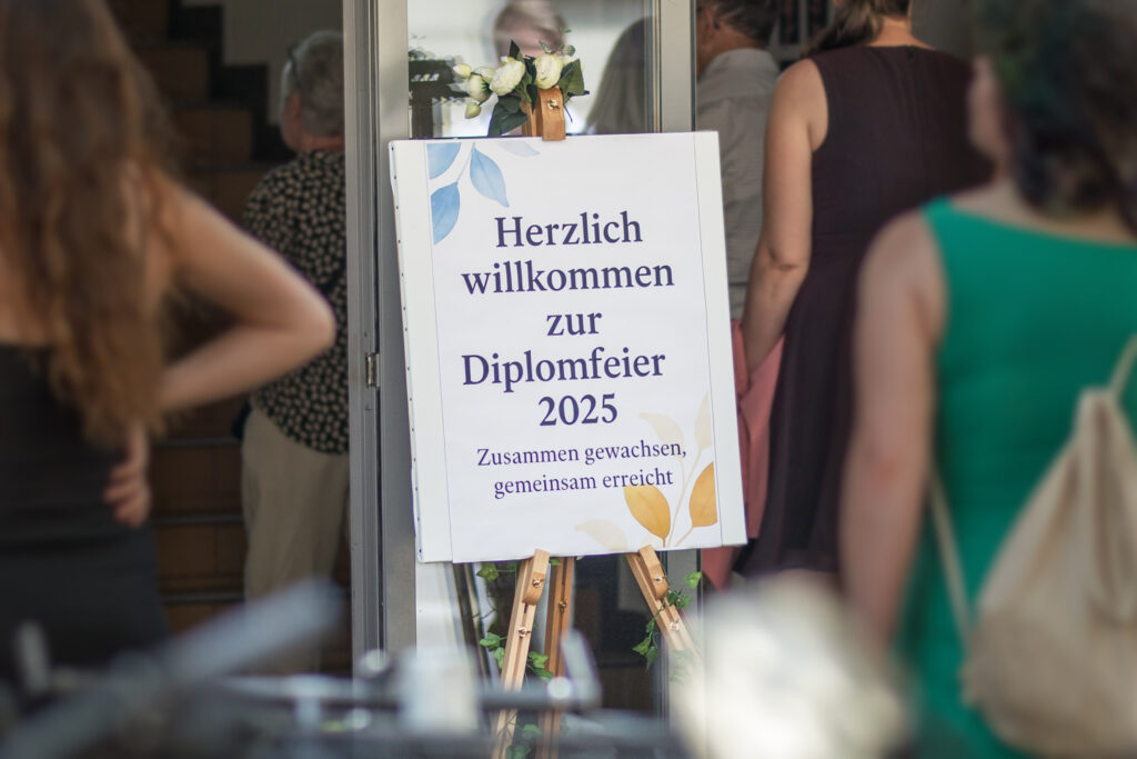 Auf dem Bild ist das mit Blumen dekorierte Willkommensschild zur Diplomfeier 2025