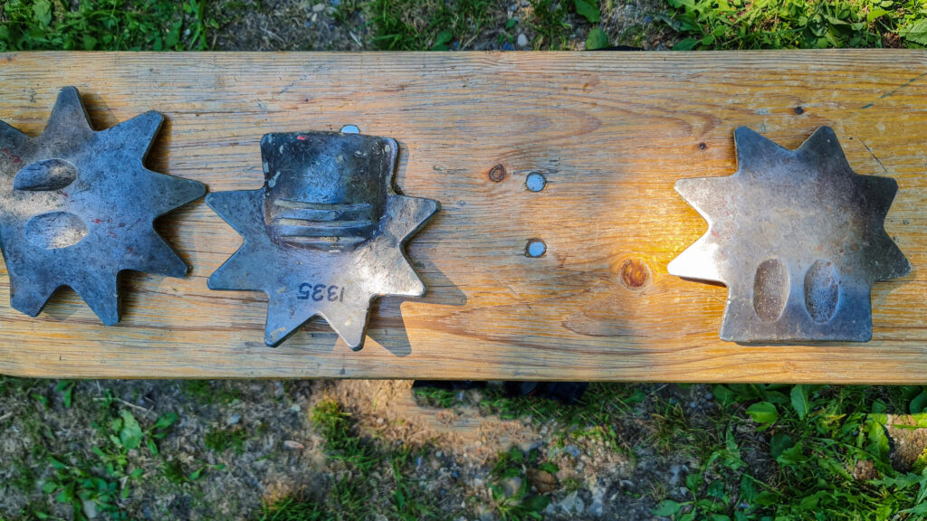 Auf einer Holzbank liegen drei Platzgen. Die Wurfgeschosse des Spiels. Sie sehen aus wie Sheriff-Sterne.